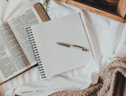 a journal on a bed with a blanket, tray, coffee