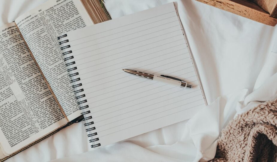 a journal on a bed with a blanket, tray, coffee