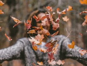 woman in a sweater throwing leaves